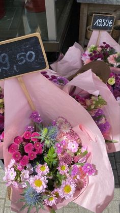 a bunch of flowers that are in some kind of pink wrapper with a sign on it