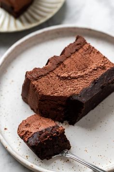 two pieces of chocolate cake on a plate with a fork