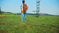 a man standing in the middle of a field next to a cell phone tower,