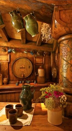 there are many vases on the table in this old fashioned kitchen with pots and pans hanging from the ceiling