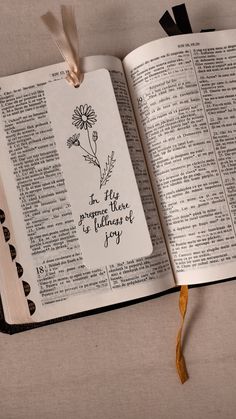 an open bible with the words in hebrew on it and a string attached to it