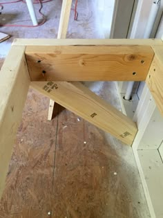 a wooden bench sitting on top of a hard wood floor next to a wall under construction