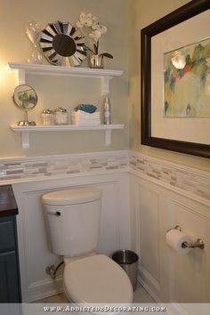 a white toilet sitting in a bathroom next to a wall mounted shelf filled with dishes