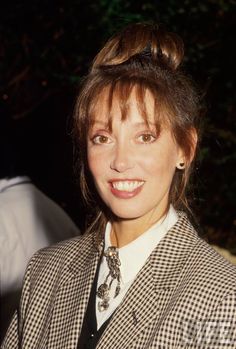 a woman wearing a suit and tie smiling at the camera