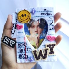 a hand holding a small photo frame with a smiley face and words on the front