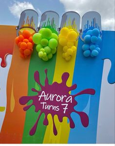 the sign for aurora turns 4 is painted in rainbow colors and has grapes on it