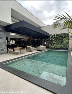 an empty swimming pool in the middle of a house with chairs and tables around it