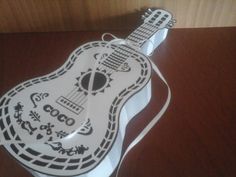 a white guitar shaped cake sitting on top of a wooden table next to a wall