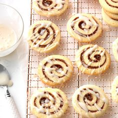 several cinnamon rolls on a cooling rack next to a glass of milk