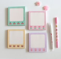 four small notepads are lined up next to a pen and flower eraser