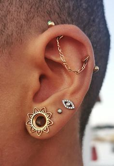 a man wearing three different ear piercings on his ears and one has a sunflower