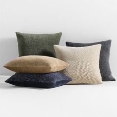 four pillows stacked on top of each other in various colors and sizes, all with different patterns