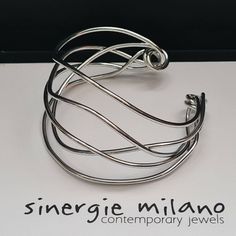 Clean and elegant lines, with an original and contemporary style. Simplicity and design. Drawing @sinergiemilano The light of the Titanium plating will make it a refined and refined accessory if worn with elegant clothes; with casual clothes it will give style and personality. For women who love wearing unusual and non-conformist accessories, without sacrificing originality. The size can be adjusted once worn, as it is open on one side. Original design SINERGIE MILANO The "Abstract" collection o Modern Silver Bracelet As Gift, Modern Silver Bracelet As A Gift, Adjustable Bracelets With A Modern Twist As A Gift, Adjustable Bracelets As Gift With A Modern Twist, Adjustable Modern Twist Bracelet As Gift, Flexible Silver Bracelets As Gift, Silver Flexible Bracelet As Gift, Flexible Silver Bracelets For Gifts, Silver Adjustable Flexible Bangle