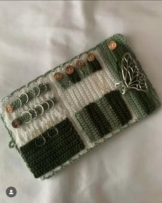 a green and white crocheted purse with buttons on it, sitting on a bed