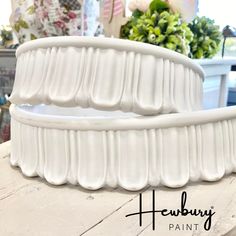 two white vases sitting on top of a wooden table