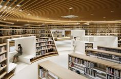 two people sitting in the middle of a library filled with books