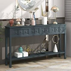 a blue console table with vases and other items on it in front of a mirror