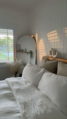 a bed with white linens and pillows in a bedroom next to a large window