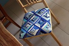 a wooden chair with a blue and white patchwork cushion on it's seat