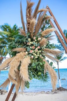 an arrangement of flowers and grass on the beach