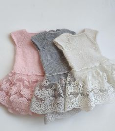 four knitted dresses are lined up on a white surface