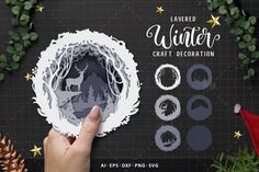 someone is making a paper cut out of a winter scene with pine cones and evergreens