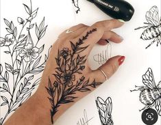 a woman's hand with flowers on it and a black marker in the background