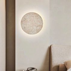 a bed sitting next to a white wall with a round light on it