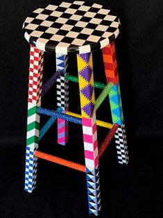 a multicolored stool made out of strips of colored paper on a black background