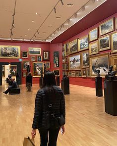 a woman walking through a museum filled with paintings