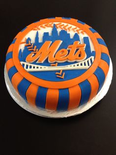 a new york mets cake with the word mets on it and an orange and blue striped design