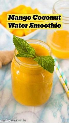 mango coconut water smoothie in a mason jar with mint on the rim and two straws next to it