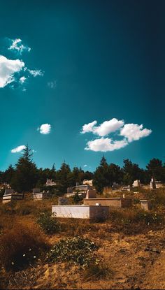 an old cemetery sits in the middle of a grassy field under a blue sky with white clouds