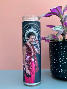 a can with an image of a man on it next to a potted plant