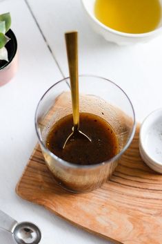 a wooden cutting board topped with a glass cup filled with liquid