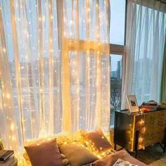 a bedroom with lights on the curtains and a bed in front of a large window