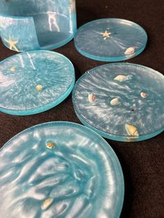 four blue plates with seashells on them sitting on a brown tableclothed surface