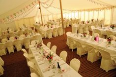 tables and chairs are set up in a tent for a wedding breakfast or reception with white linens and pink flowers