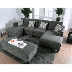 a living room with grey couches and pillows on the floor, coffee table in front of it