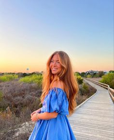 a woman in a blue dress standing on a boardwalk