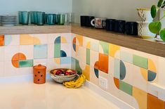 a bowl of fruit sitting on top of a counter next to cups and saucers