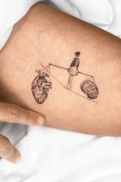 a person with a tattoo on their leg holding a string attached to the heart and brain