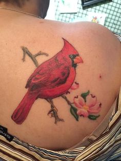 a woman's back with a red bird on it and flowers around her neck