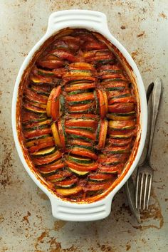 a casserole dish filled with sliced vegetables and topped with a fork next to it