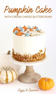 pumpkin cake with cream cheese buttercream on a pedestal and two small pumpkins