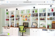 a home office with white bookcases and green chair in front of the desk