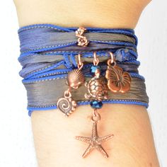 "This listing is for one beach silk wrap bracelet.  This ocean silk wrap bracelet features a lovely hand-dyed silk ribbon in shades of deep blue and brown, approximately 1/2\" wide and 42\" long, adorned with a copper ring of flowers and dangling copper charms in a beach theme.  The charms showcase two-sided, 3D copper shapes, including a hibiscus flower, a charming turtle surrounded by cobalt crystals, a starfish, a stylized heart, and a seashell.  This yoga bracelet is carefree and gorgeous, p Braille Jewelry, Silk Ribbon Jewelry, Bracelet Ocean, Beachy Bracelets, Silk Wrap Bracelets, Hand Dyed Silk Ribbon, Silk Bracelet, Boho Bangle, Ribbon Jewelry