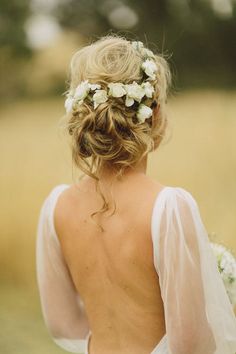 the back of a woman's head with white flowers in her hair and veil