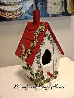 a birdhouse with ivy growing on it's roof and red shingled roof