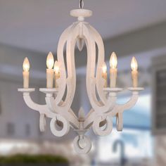 a white chandelier hanging from the ceiling with lit candles in front of it